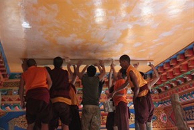 僧侶與彩繪家一起將完成的繪畫貼在寺院入口的天花板上